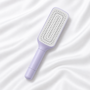 Brosse à cheveux lilas avec picots rétractés et manche rotatif, posée sur fond blanc