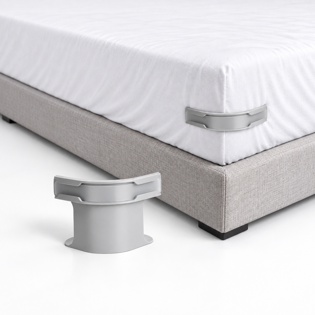 Maintien de draps gris présenté seul et installé au coin d'un matelas recouvert d'un drap blanc