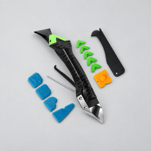 Outil de calfeutrage noir avec racloir métallique et embouts verts, bleus et jaune sur fond gris clair
